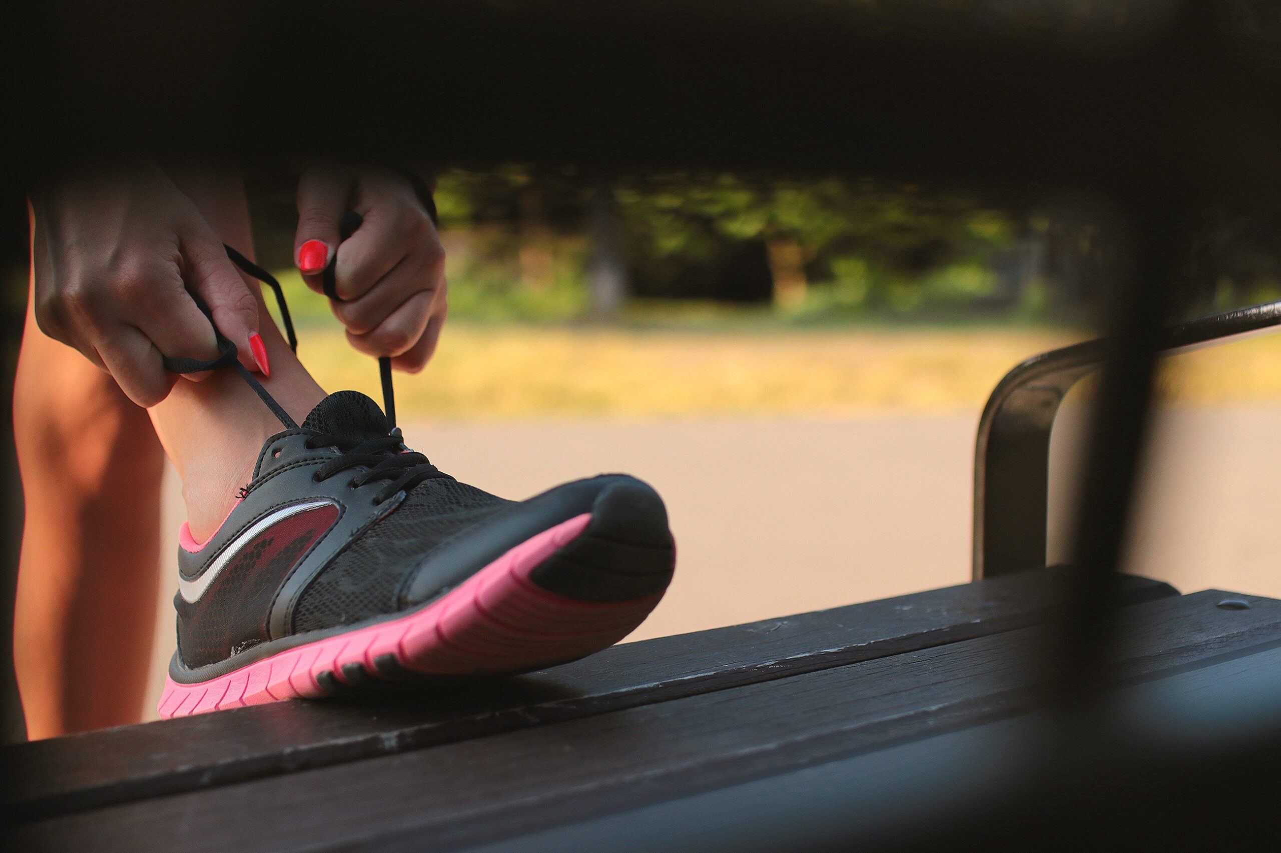 hands with pink fingernails tie laces on tennis shoes